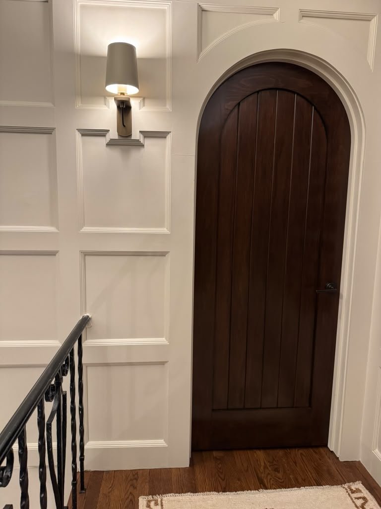 Arched wood door with custom wall paneling