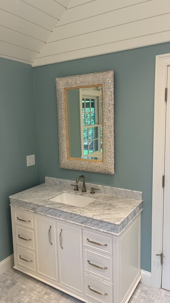 Bathroom vanity with marble top and shiplap ceiling