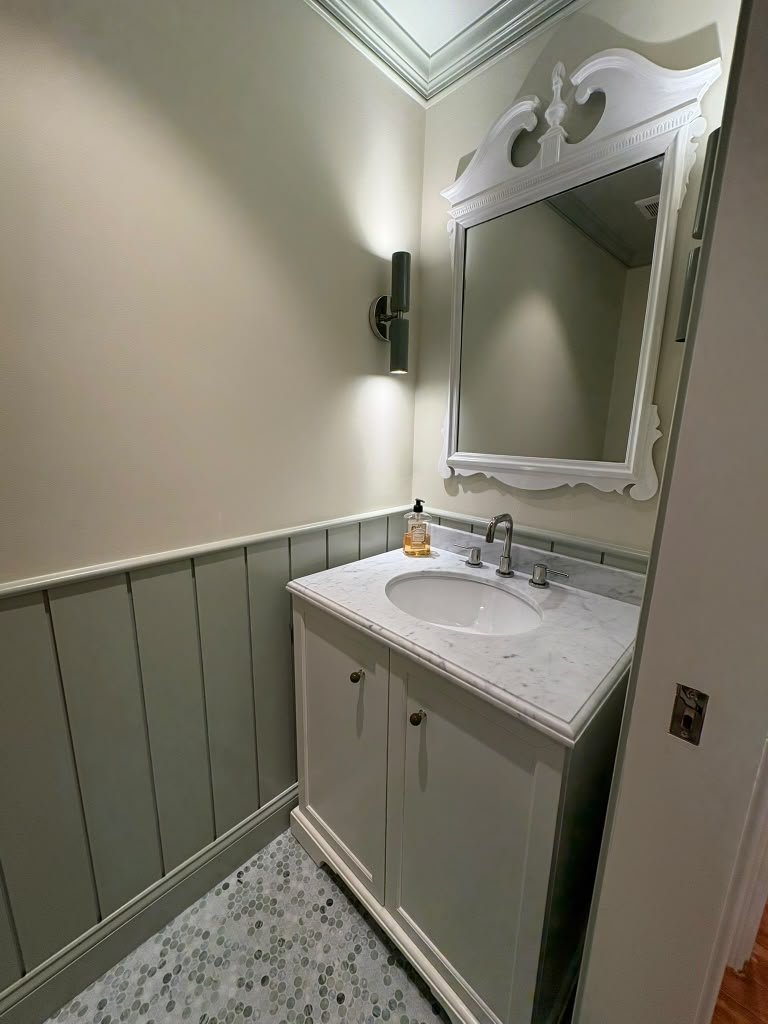 Powder room with marble-top vanity and vertical wainscot